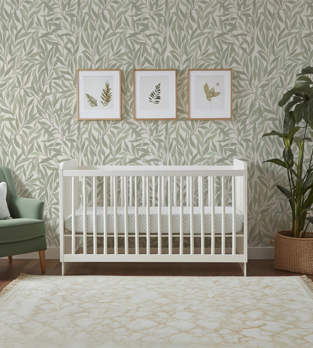 Great Willow Light Green botanical nursery wallpaper by Funky Paper Co  with white crib and framed botanical prints