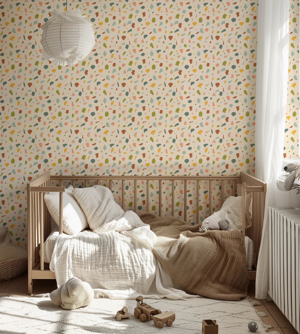 Southwest boho terrazzo wallpaper with green, teal, and burnt orange speckles on a creamy yellow background in a nursery.
