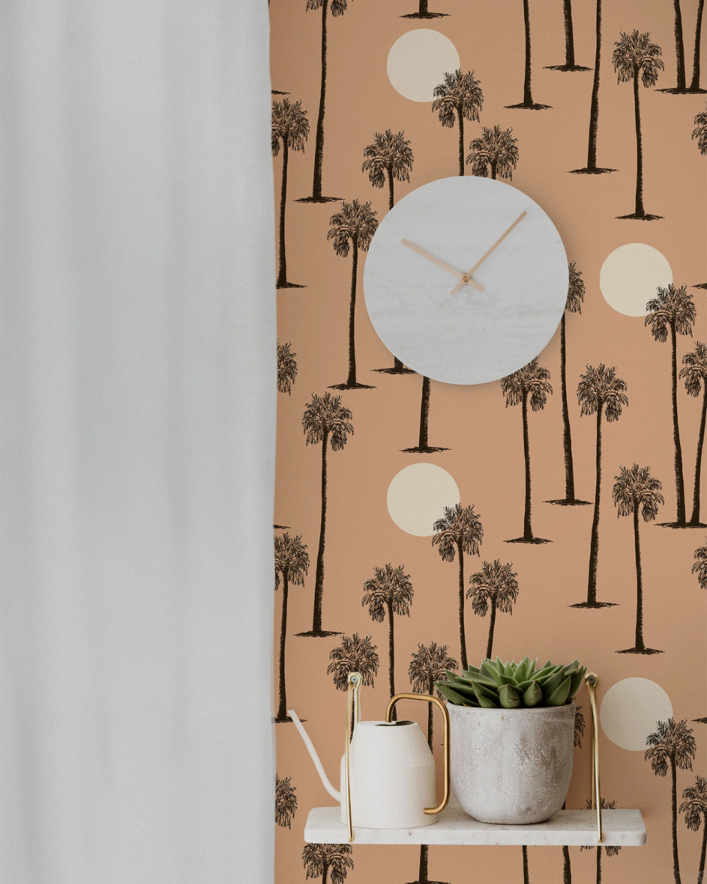 A styled interior scene showing a Pal Springs peach wallpaper with a black palm tree and cream canyon sunset pattern, a round white wall clock, a white floating shelf with a small succulent in a textured pot, and a white curtain on the left.